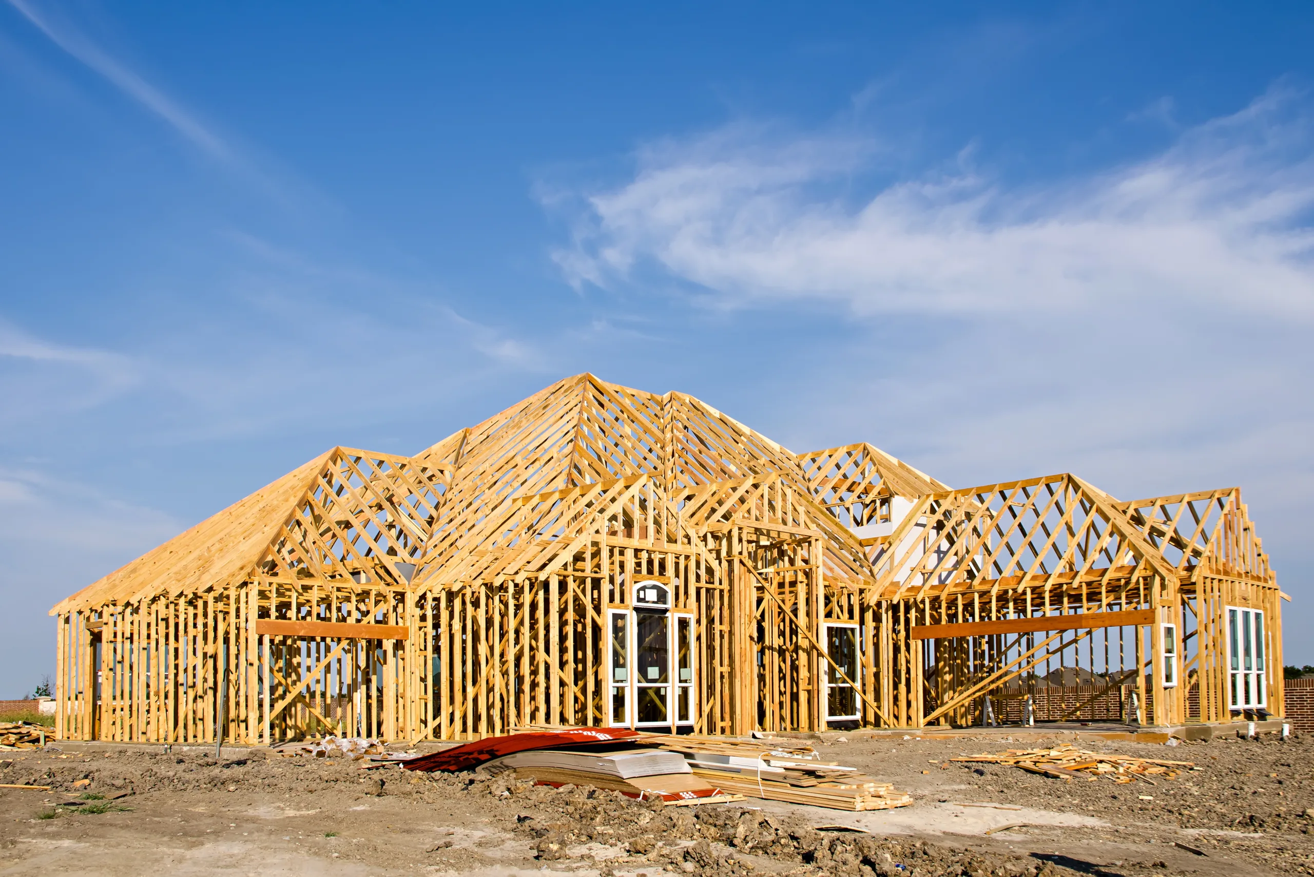 New Construction Page- Photo panel 1- 11 New residential home under construction with wooden framing against a blue sky.